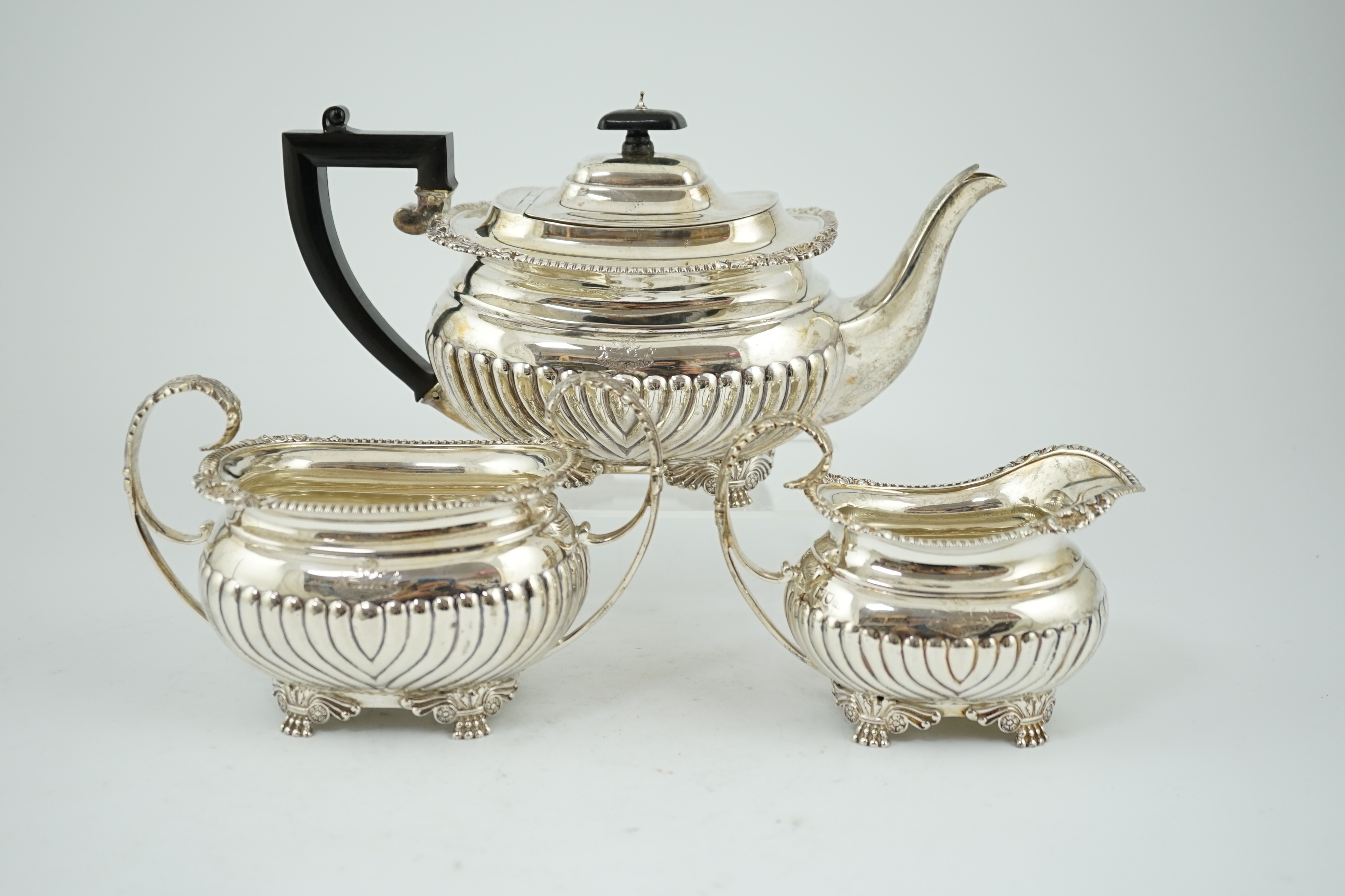 A late Victorian demi fluted silver three piece tea set, by The Barnards, of oval form, with engraved armorial, on winged paw feet, London, 1899, gross weight 44.4oz. Condition - good